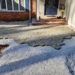 Flagstone patio being laid around existing brick front porch
