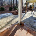 Flagstone patio being laid, small excavator nearby.