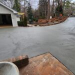 Freshly poured concrete driveway leading to a two‑car garage