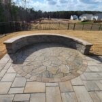 Curved stone seating wall around a circular patio in a backyard